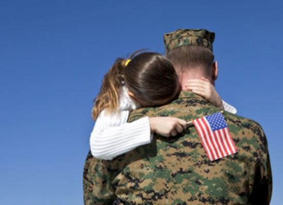 little girl hugging a soldier and holding a flag